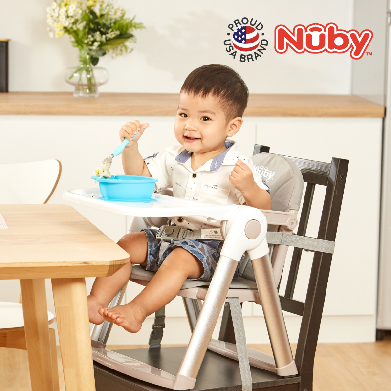 Astra Family A baby eating food in a foldable booster seat.